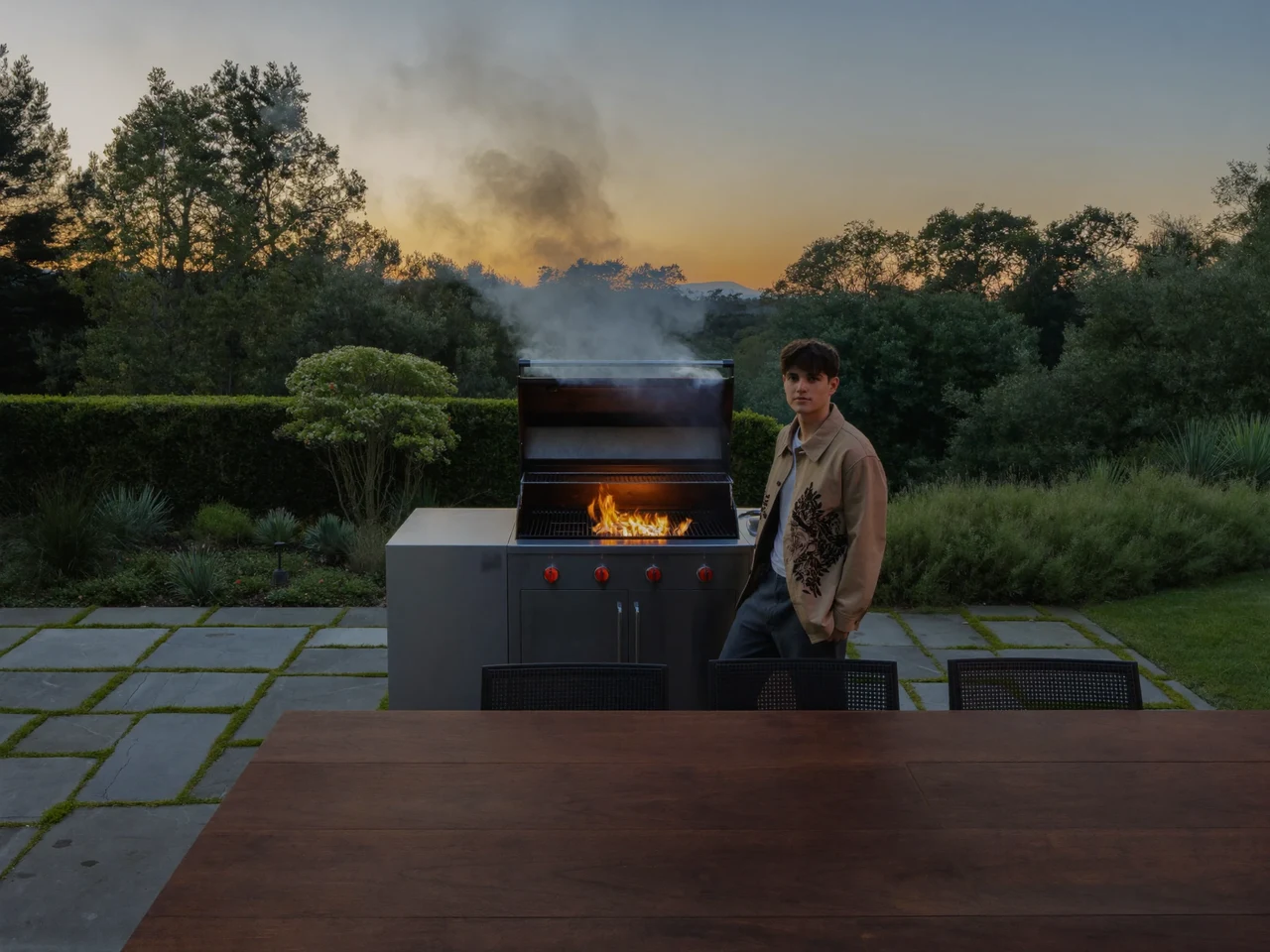 Illustration: Gartenterrasse in der Dämmerung mit glühendem Holzkohlegrill